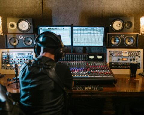 music producer sitting in a studio in front of a computer and console