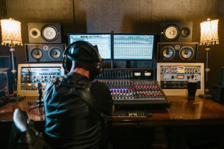 music producer sitting in a studio in front of a computer and console